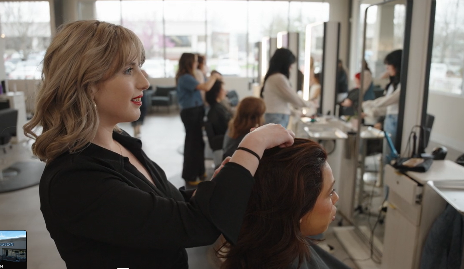 Stylist styling a client's hair in a bright, busy salon