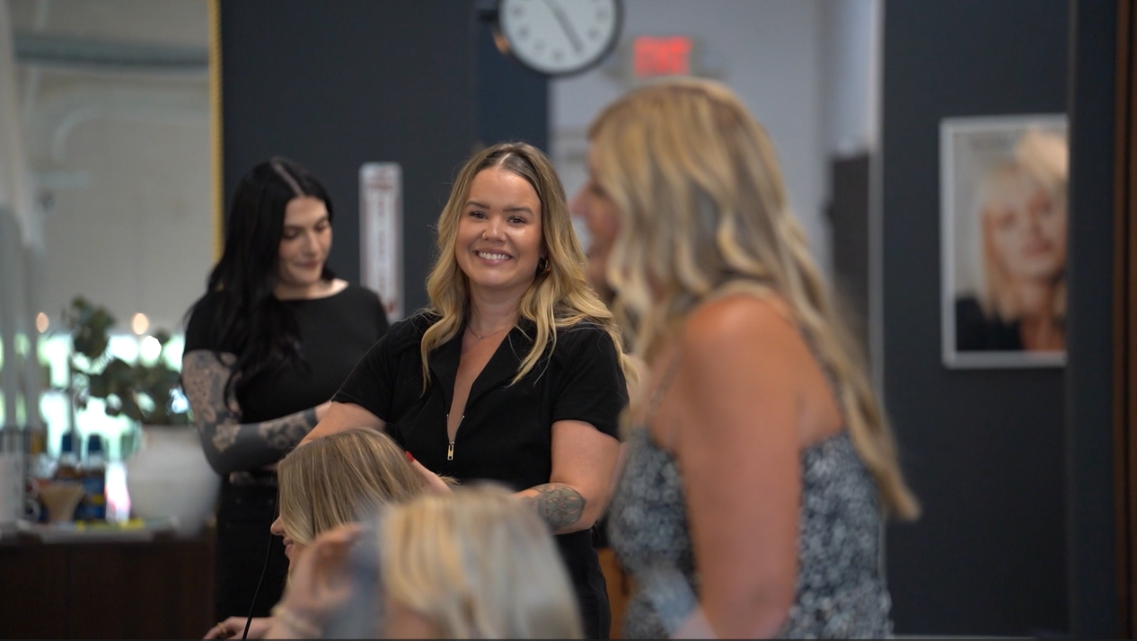 Smiling stylist with customer in busy salon